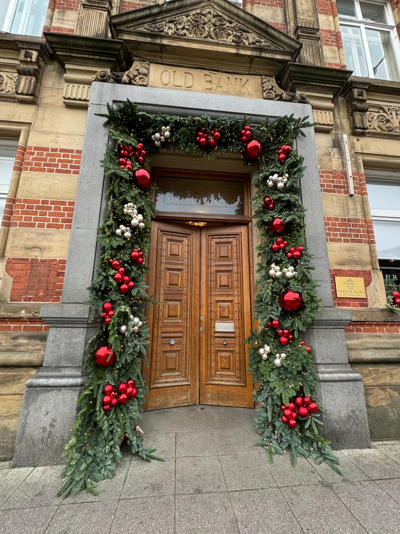Christmas entrance installation with red baubles and lush green foliage at a city venue