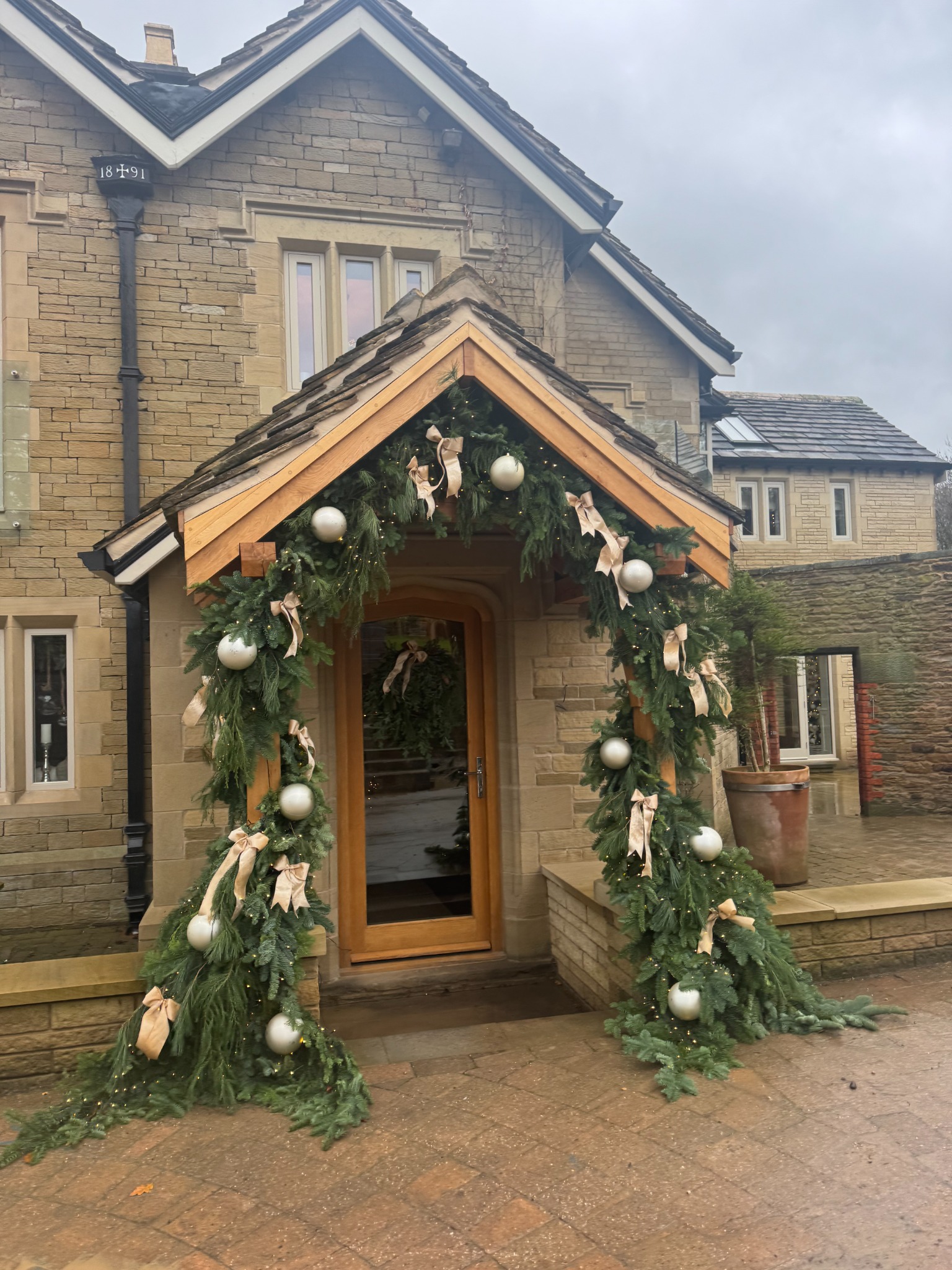 Evergreen Christmas doorway garland with champagne bows and baubles at a country house