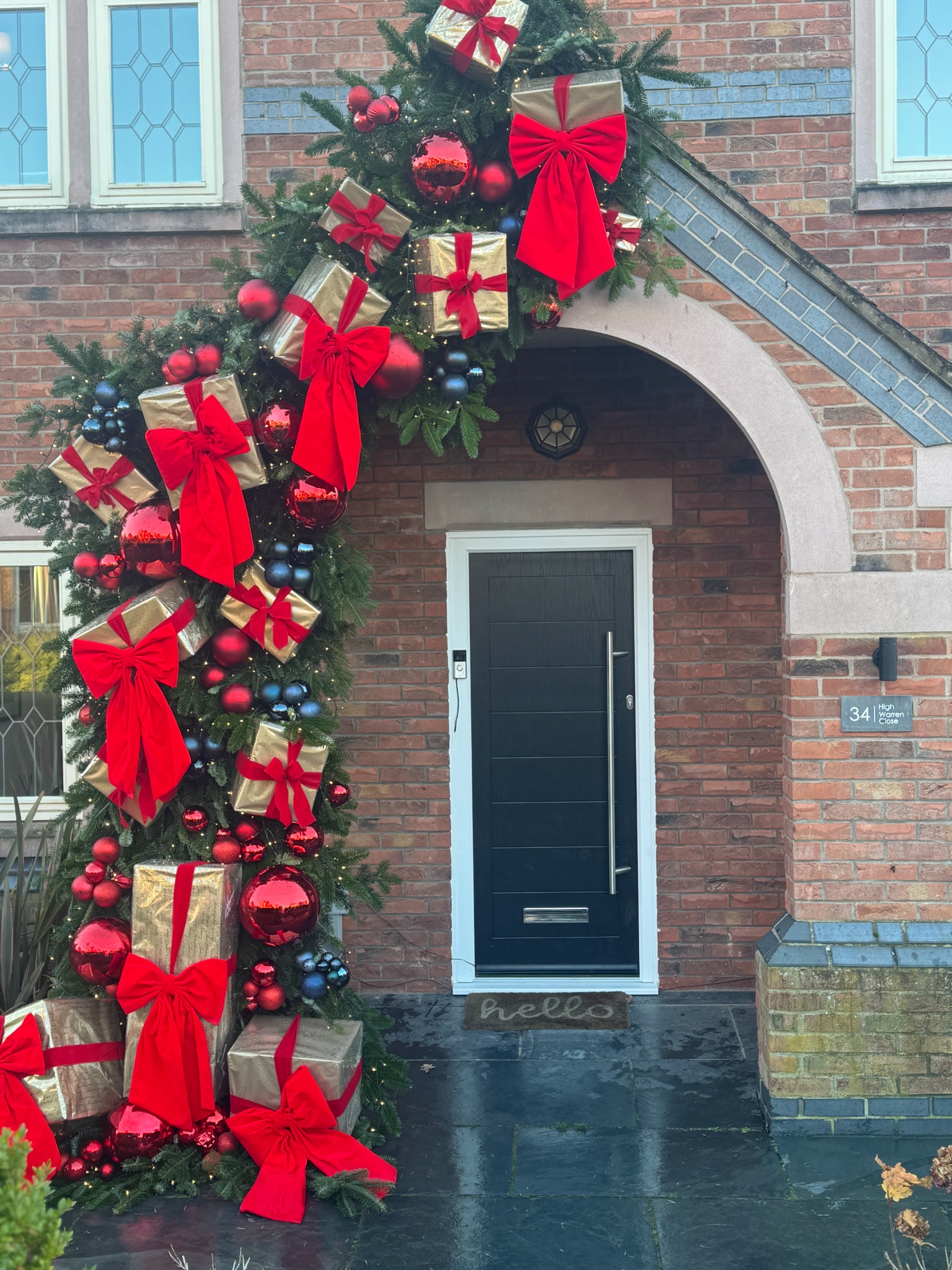 Festive greenery with gold presents and red bows framing a private entrance