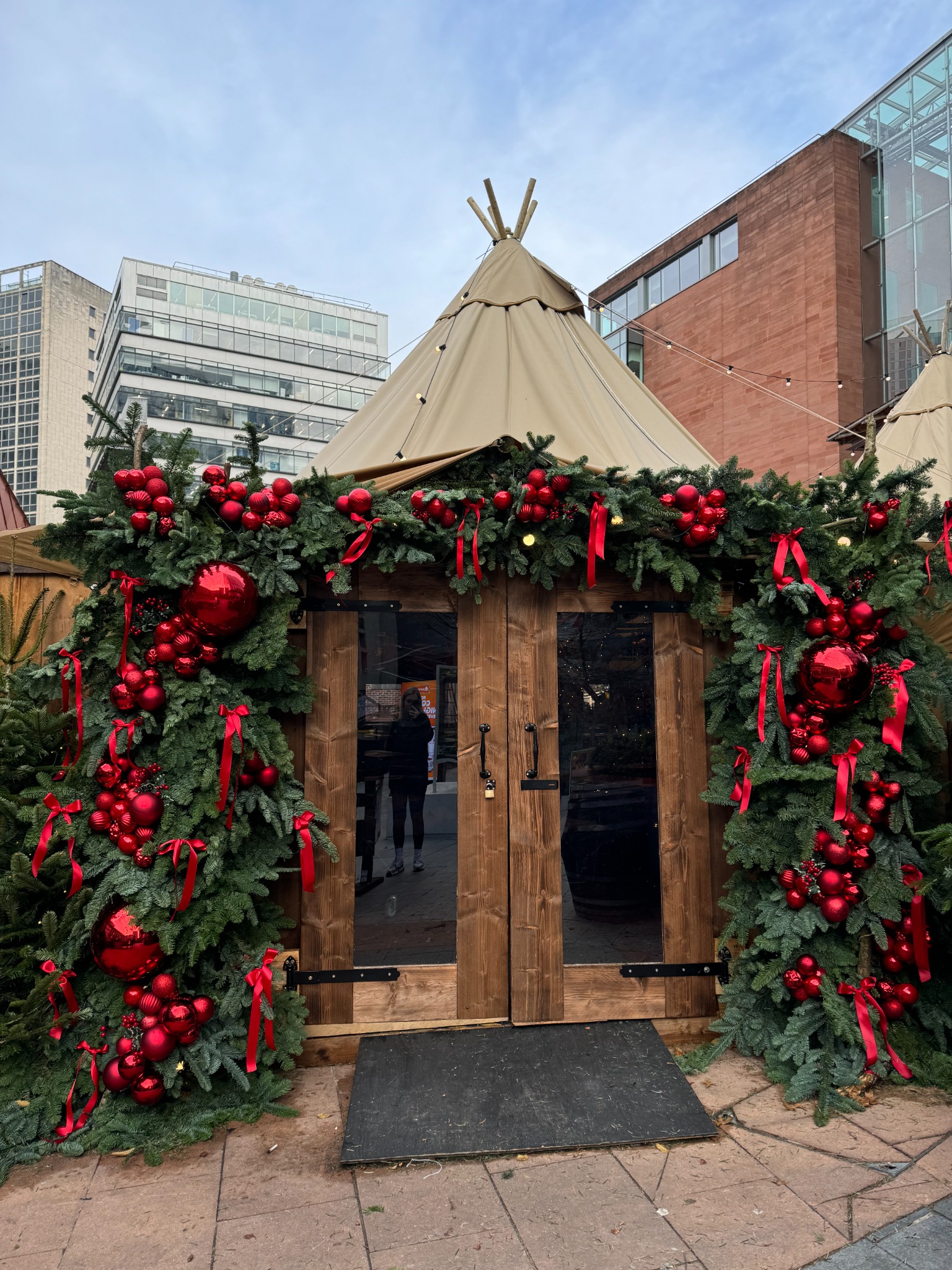 Christmas styling with evergreen garlands and red baubles around an outdoor hospitality entrance