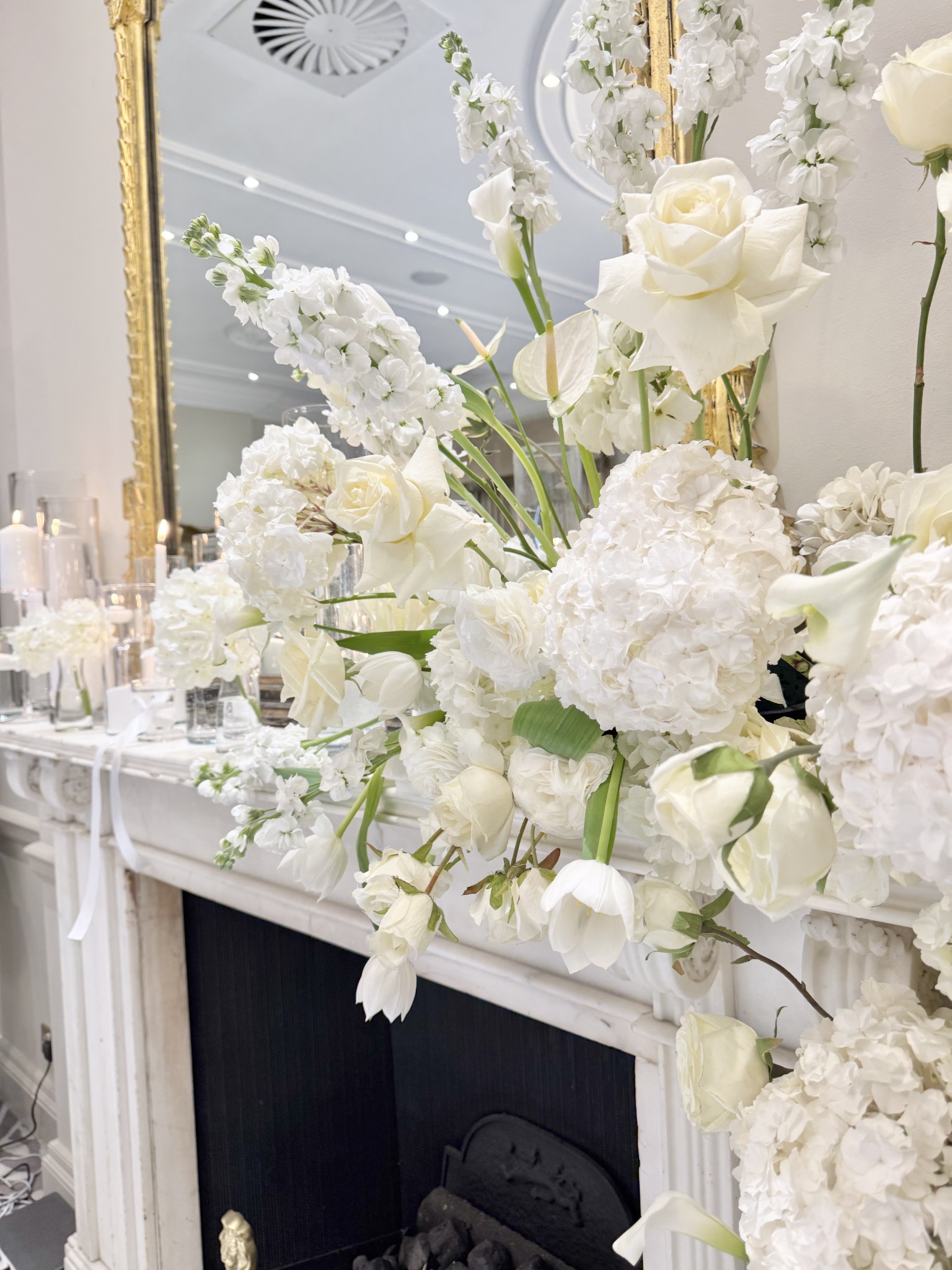 Elegant all-white floral styling displayed across a mantelpiece for an event