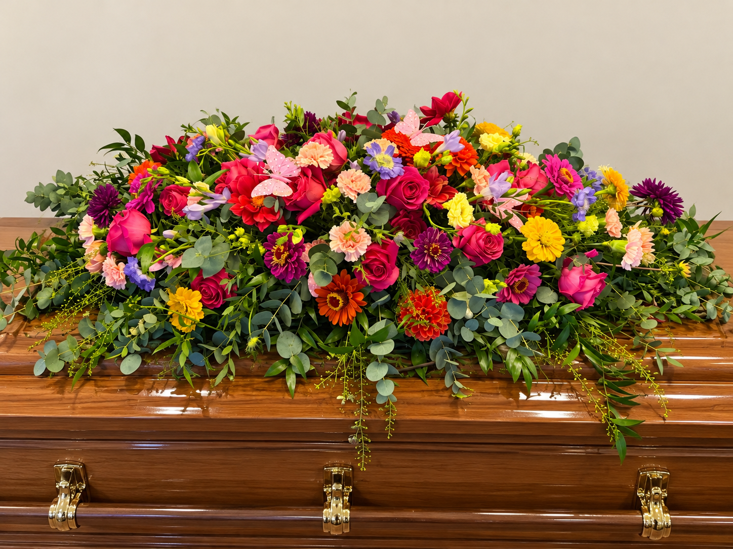 Vibrant bespoke flowers arranged along a polished wooden coffin