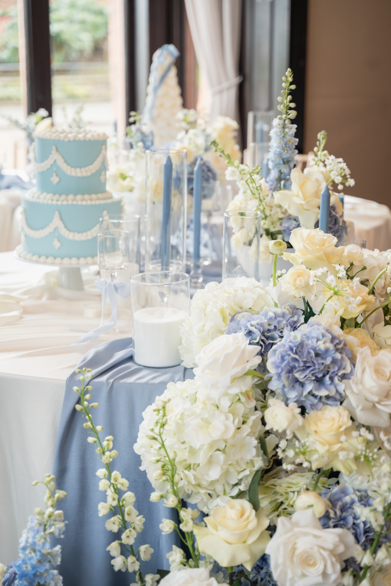 Blue and ivory wedding reception flowers, candles, table linens and cake