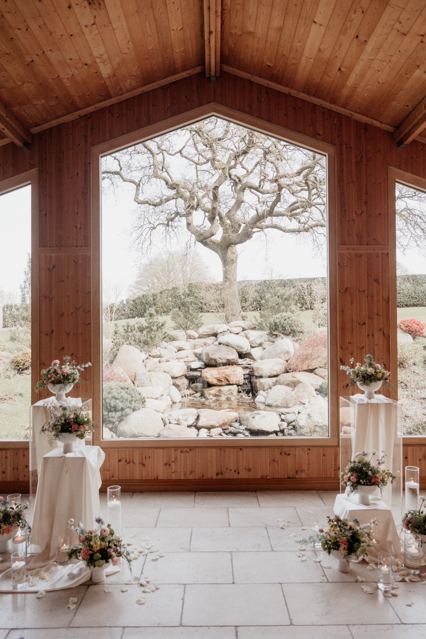 Wedding ceremony flowers and pedestal arrangements in a timber-framed venue